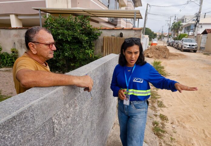 Assistente social conversa com morador durante visita domiciliar do Programa Socioambiental da Casan em Florianópolis.