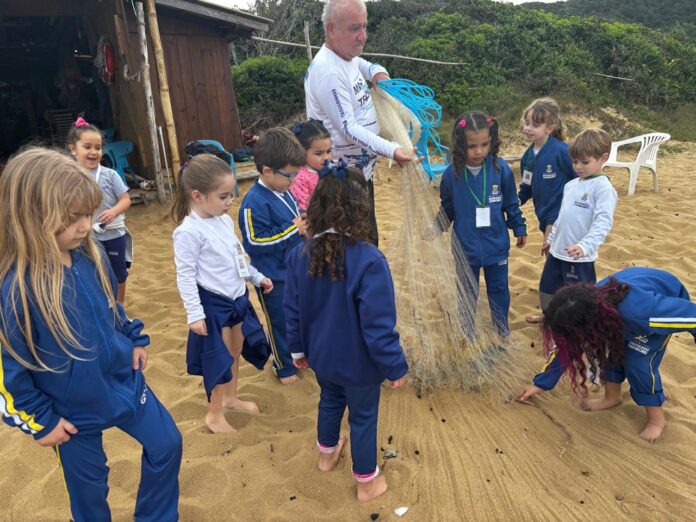 Crianças da Educação Infantil de Balneário Camboriú em atividade sobre a pesca artesanal da tainha, com pescadores e redes de pesca.